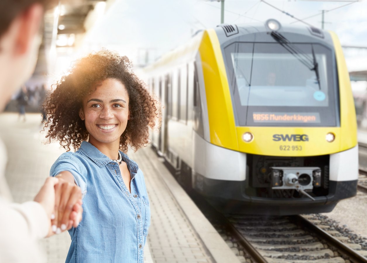 Ein Pärchen steht am Bahnsteig während ein Zug einfährt.