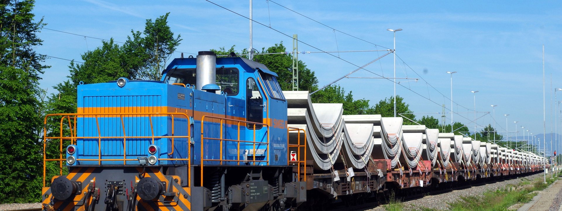 Güterzug mit großen halbrunden Betonteilen als Ladung