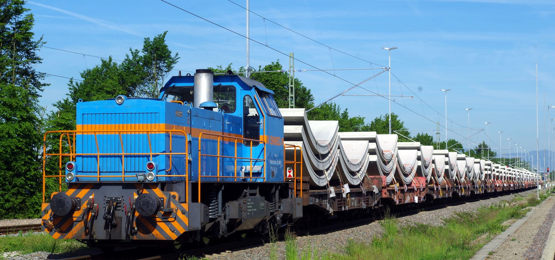 Güterzug mit großen halbrunden Betonteilen als Ladung